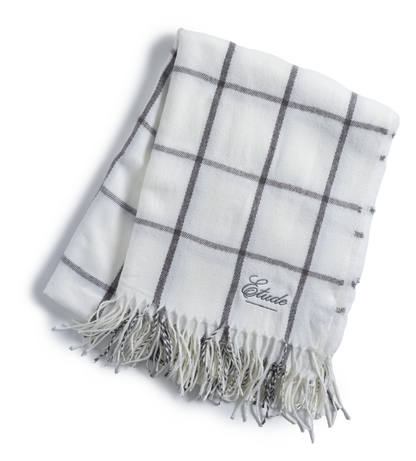 White plaid scarf with fringe and the word "Etude" embroidered on it.